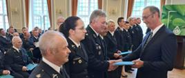 Zdjęcie przedstawia wręczenie umowy dofinansowań dla jednostki ochotniczej straży pożarnej w Mielęcinie