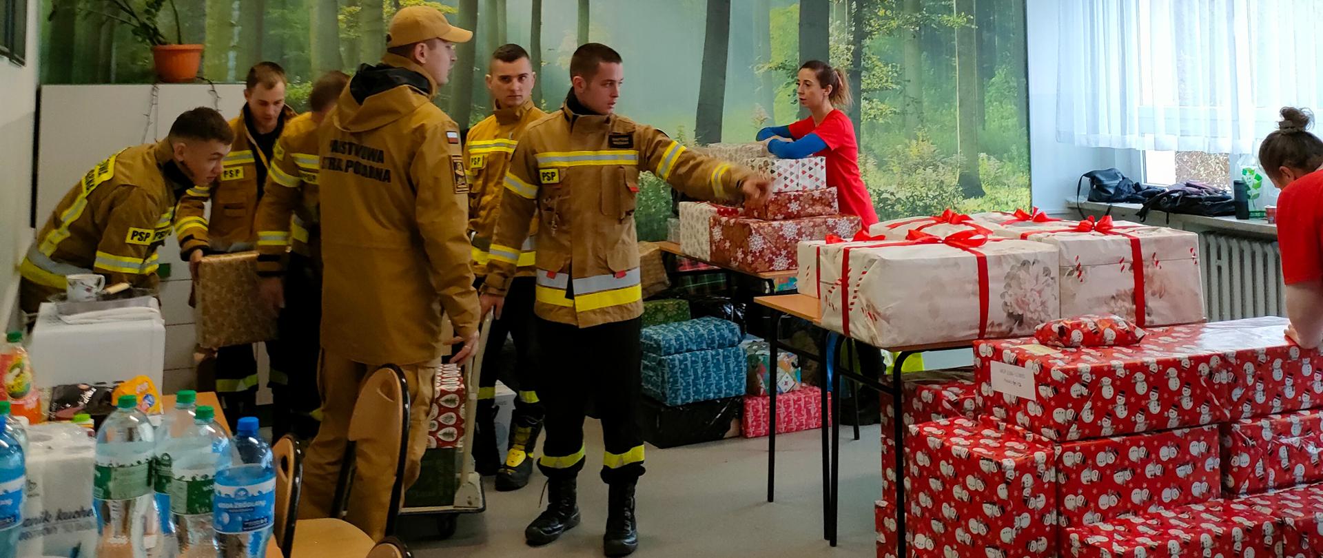 Sześciu strażaków i wolontariusze w siedzibie akcji Szlachetna Paczka sortują paczki, które będą dostarczane do osób potrzebujących