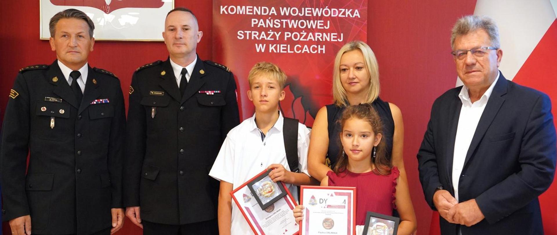 Odznaczeni odznaką Iuvenis Forti: Paulina i Grzegorz Orlińscy oraz Wojewoda Świętokrzyski Józef Bryk, Świętokrzyski Komendant Wojewódzki PSP st. bryg. Marcin Charuba, Komendant Miejski PSP w Kielcach st. bryg. Mariusz Góra i mama bohaterskich dzieci