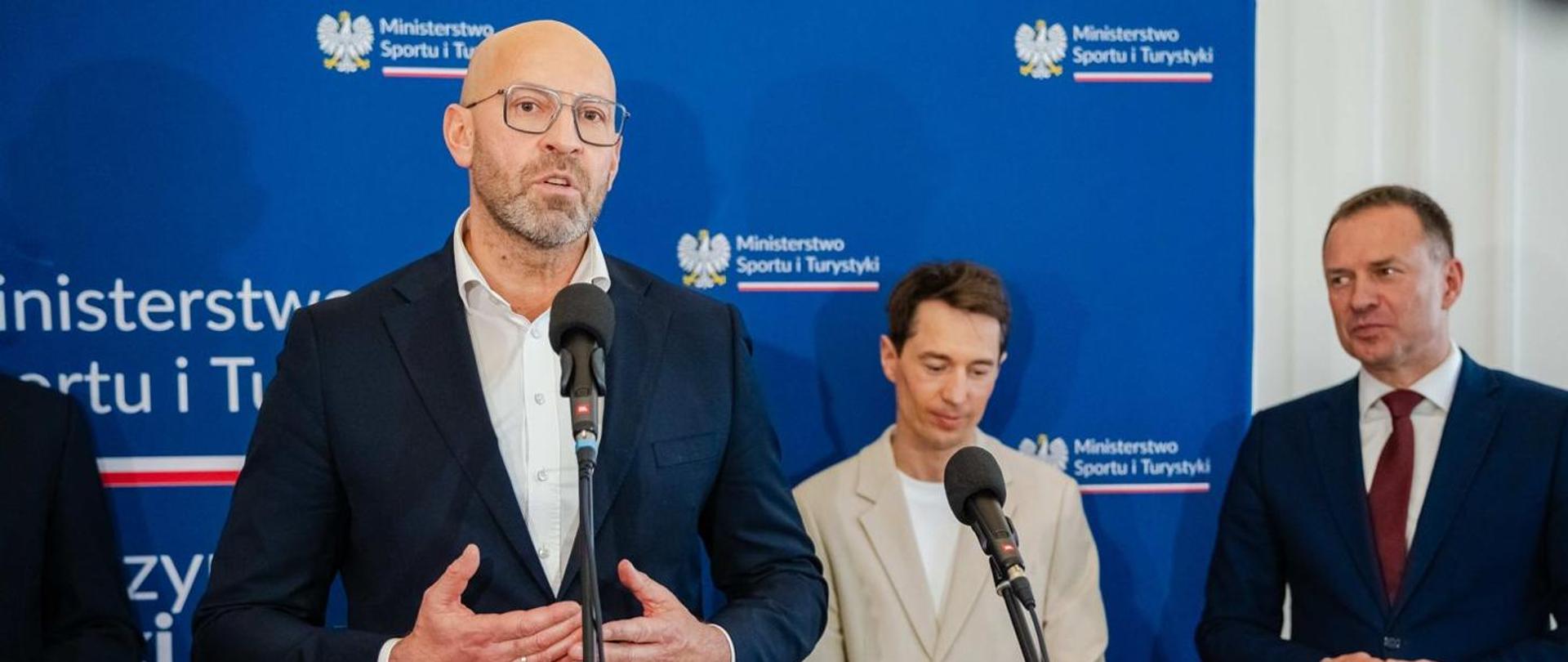 Minister of Sport and Tourism Jakub Rutnicki speaks into the microphone. In the background: Kamil Stoch and Secretary of State Piotr Borys 