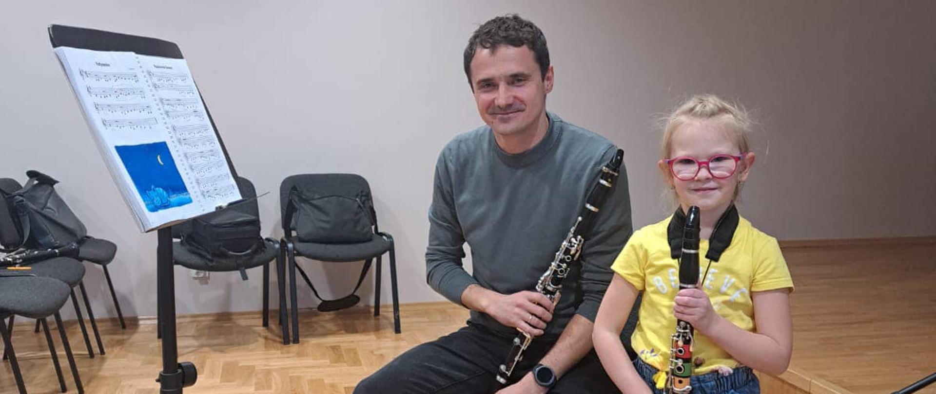 Uczennica i wykładowca w trakcie warsztatów, trzymają klarnety, patrzą w obiektyw kamery
