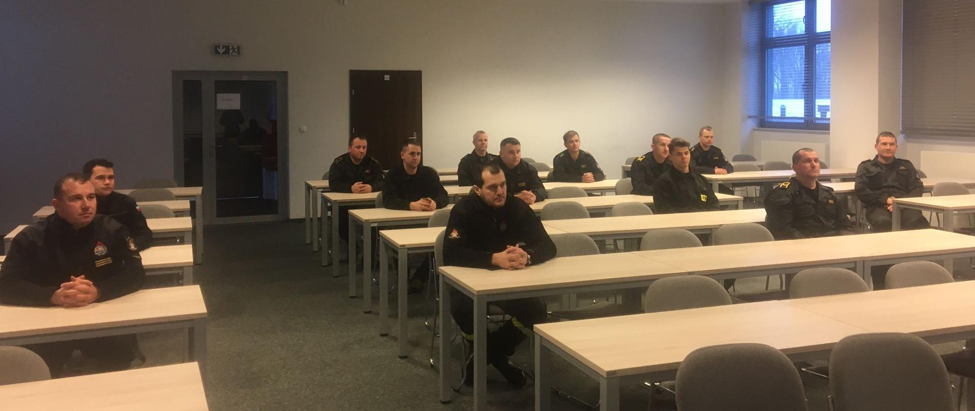 Strażacy siedzą w sali wykładowej na zakończeniu szkolenia.