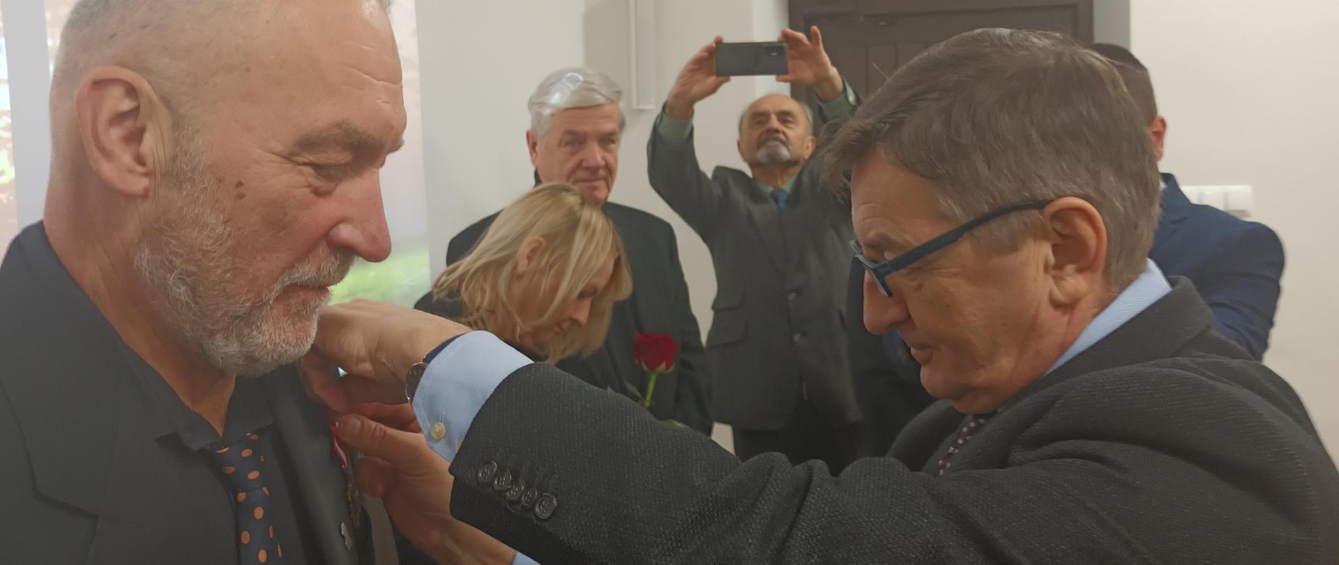 Na zdjęciu po lewej stronie widzimy Piotra Biesa odbierającego z rąk Marszałka Sejmu Marka Kuchcińskiego znajdującego się po prawej stronie. 