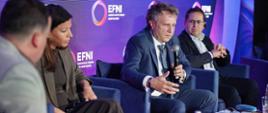 Na zdjęciu wiceminister funduszy i polityki regionalnej Jacek Karnowski w towarzystwie innych uczestników spotkania na scenie w trakcie dyskusji
