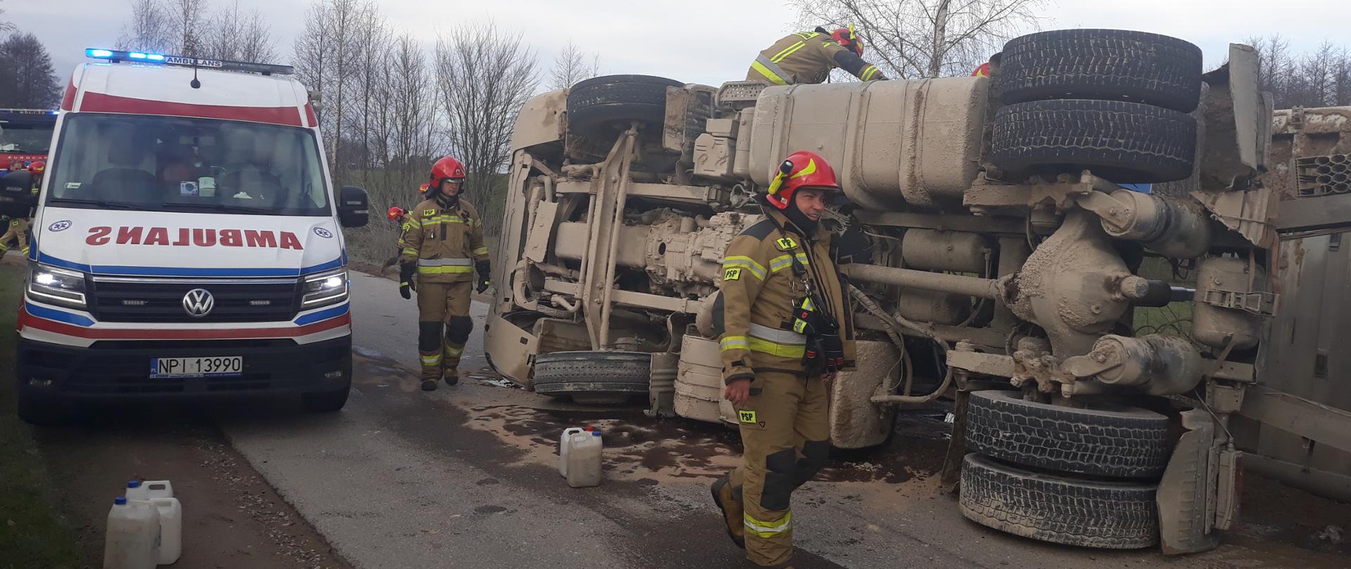 Samochód ciężarowy leży na boku na drodze asfaltowej
