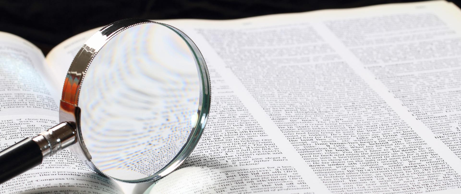 Dictionary with an magnifying glass on top