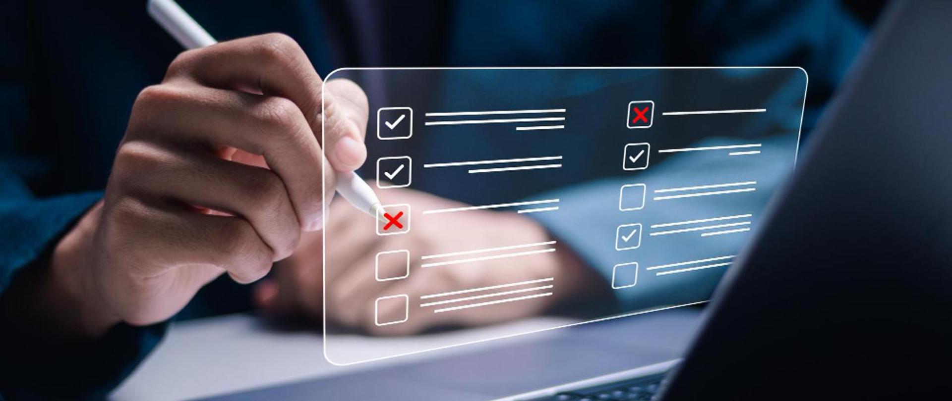 Zdjęcie przedstawia dłoń trzymającą długopis oraz przezroczysty, wirtualny formularz z listą kontrolną – widoczne są zaznaczone i niezaznaczone pola wyboru. Grafika symbolizuje ocenę i kontrolę czynników rakotwórczych, mutagennych i reprotoksycznych w środowisku pracy.