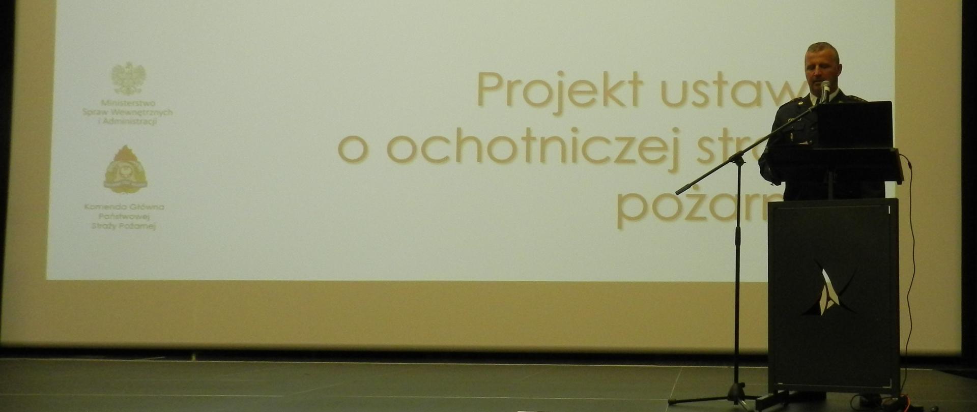 Funkcjonariusz PSP w umundurowaniu wyjściowym podczas przemawiania. 