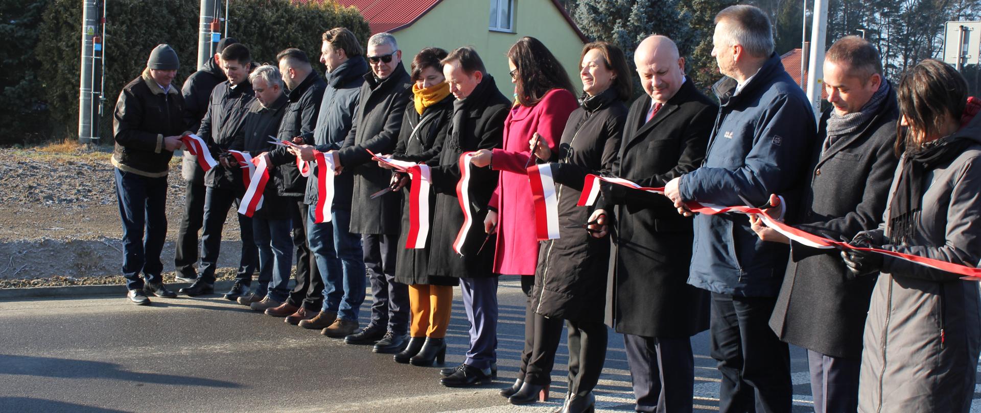 uczestnicy uroczystości z przeciętą wstęgą i nożyczkami stoją na obwodnicy Lubaczowa