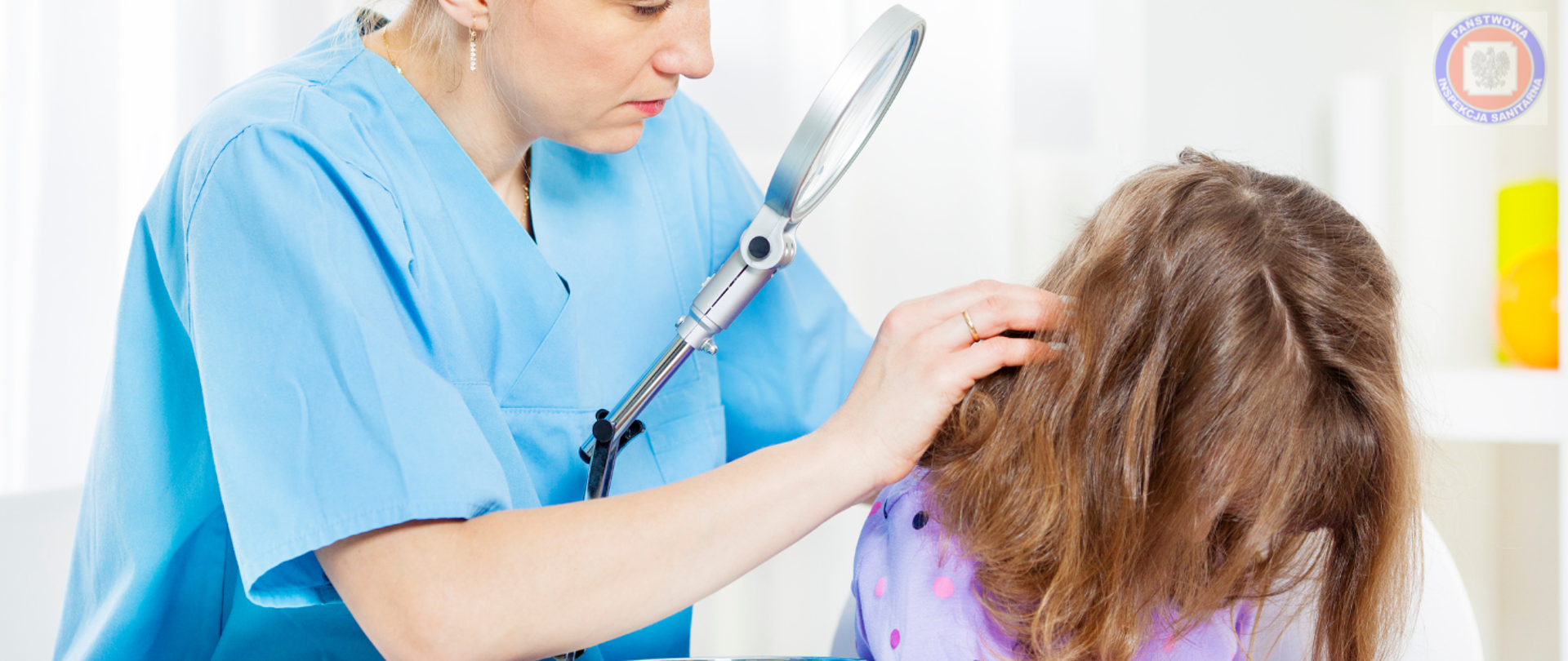 Na zdjęciu widać lekarkę lub higienistkę, która przy użyciu lupy powiększającej sprawdza włosy młodej dziewczynki