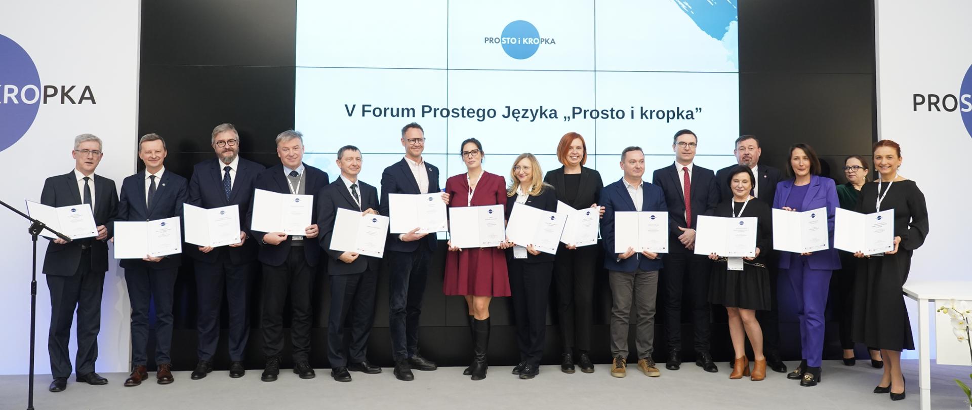 Kilkanaście osób stoi obok siebie na scenie