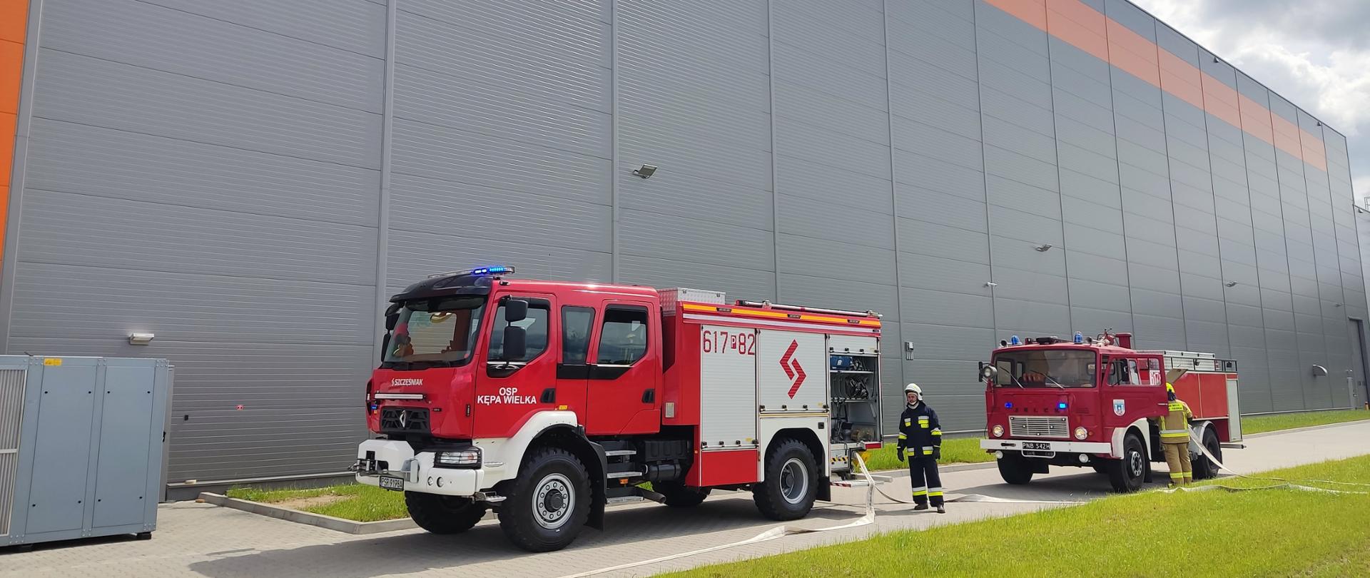 Strażacy budujący linię główna gaśniczą z pojazdu oraz zasilanie wodne podczas ćwiczeń na obiekcie firmy produkcyjnej