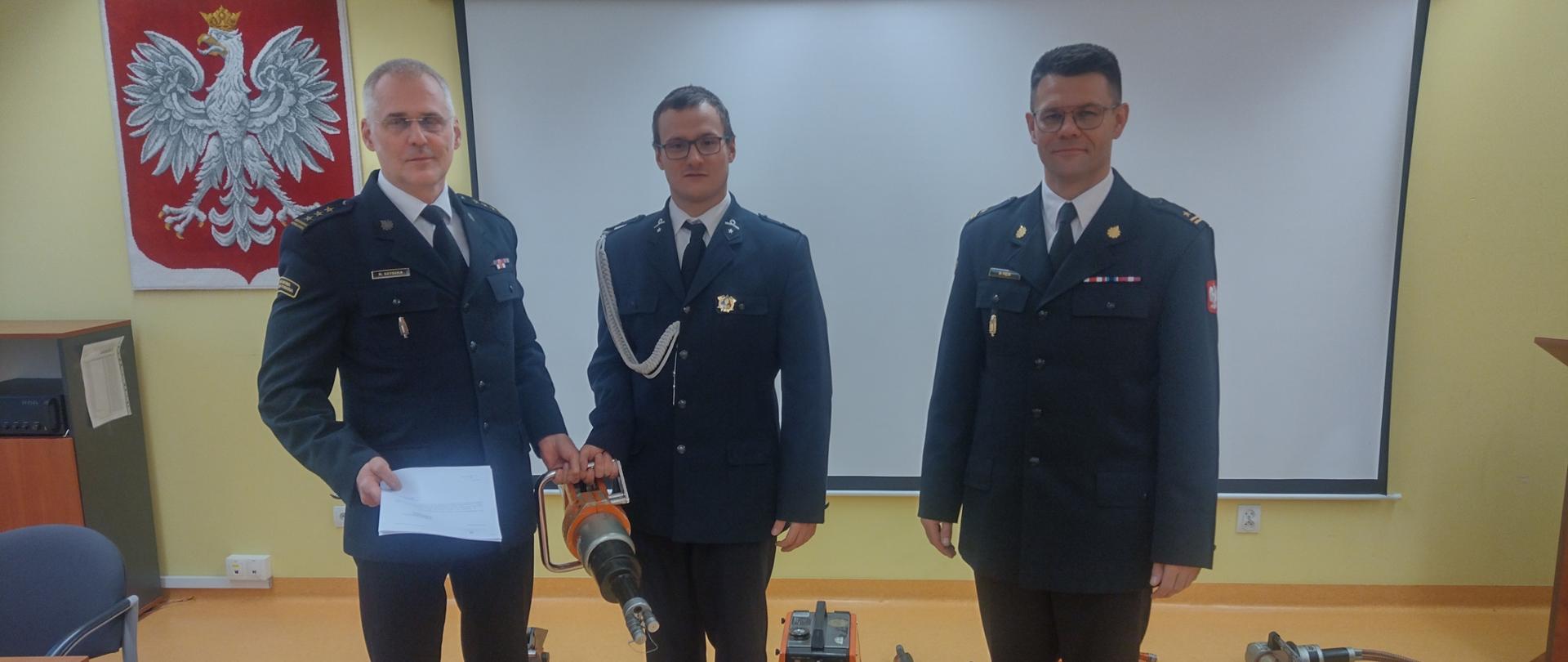 Strażacy w mundurach wyjściowych siedzą przy stołach w sali dydaktycznej w Komendzie Miejskiej PSP w Wałbrzychu, 