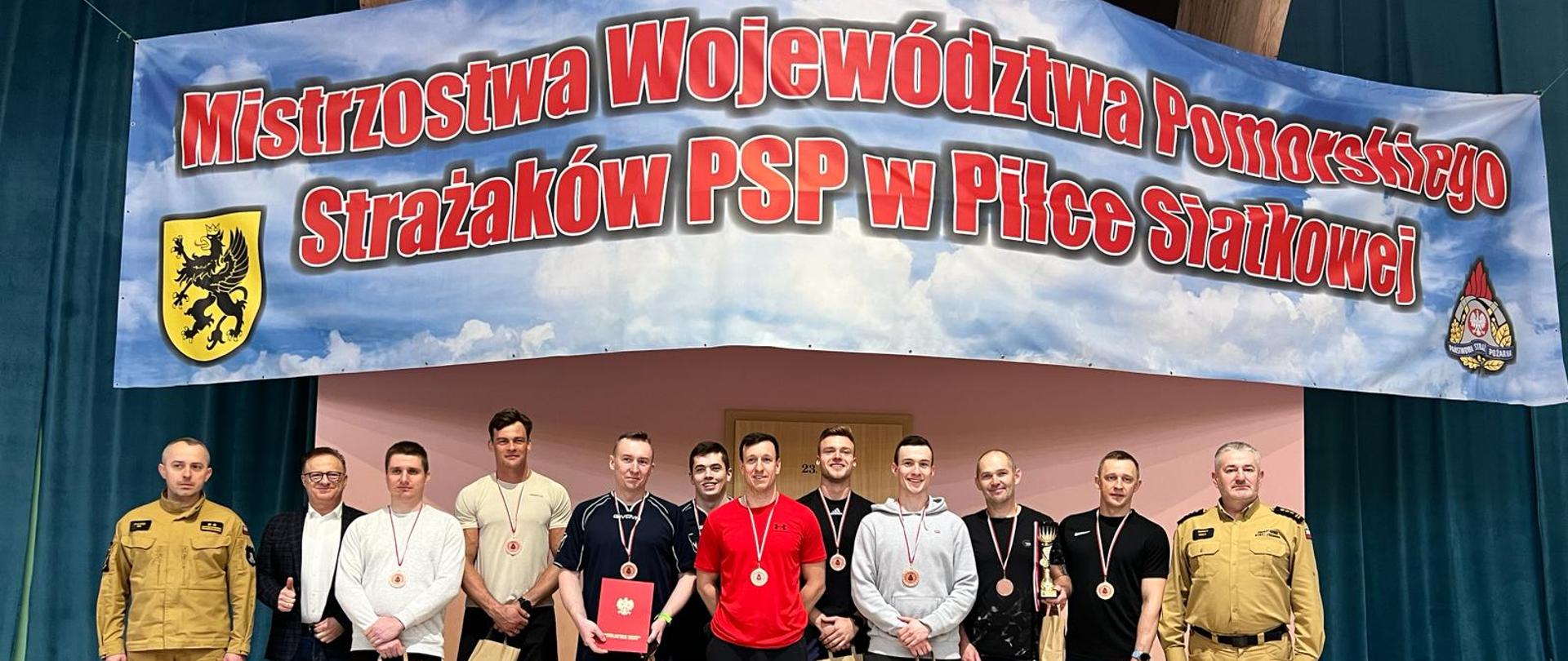 Wręczenie pucharu, medali oraz dyplomu przez Zastępcę Komendanta Wojewódzkiego PSP w Gdańsku Pana st. bryg. Mariana Hincę oraz Komendanta Powiatowego PSP w Kartuzach Pana bryg. Pawła Maja dla KP PSP w Pucku za zajęcie 3 miejsca w Mistrzostwach Województwa Pomorskiego w piłce siatkowej. Na zdjęciu funkcjonariusze ustawieni w szeregu . Od lewej na zdjęciu Pan bryg. Paweł Maj, Funkcjonariusze KP PSP w Pucku st.asp. Przemysław Wojtinski, ogn. Krzysztof Totzke, ogn. Adam Groen, st.str. Szymon Miler, mł. asp. Jacek Stachowicz, mł kpt. Szczepan Zieliński, st.str. Wojciech Stachowicz, mł. asp. Mariusz Roeske, st. ogn. Mirosław Rost, Pan st. bryg Marian Hinca. Nad funkcjonariuszami wisi baner z napisem ,, Mistrzostwa Województwa Pomorskiego Strażaków PSP w Piłce Siatkowej"