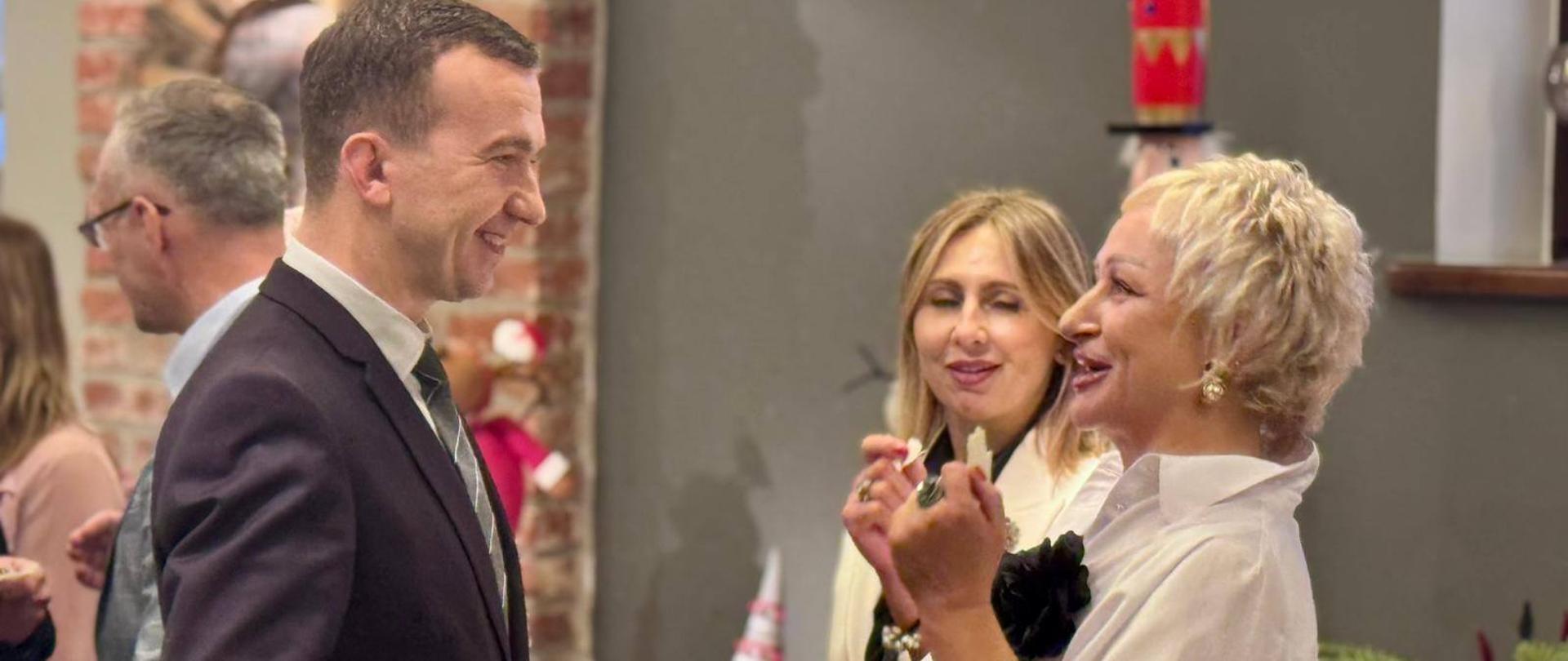 Mężczyzna dzieli się opłatkiem z kobietą 