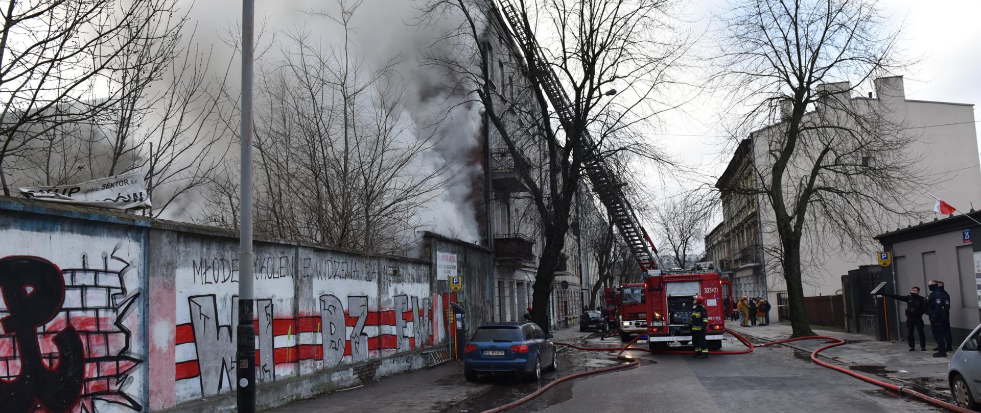 Samochód gaśniczy w oddali na środku ulicy obok palący się budynek