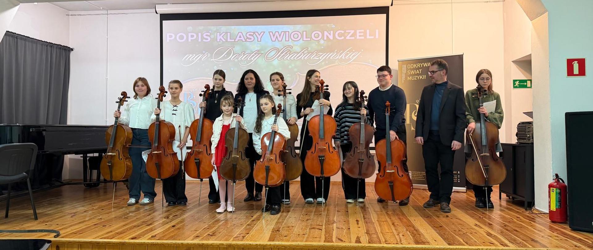 Zdjęcie przedstawiające wykonawców podczas popisu klasy wiolonczeli mgr Doroty Straburzyńskiej, który odbył się 1 grudnia 2025 r. w auli szkoły.