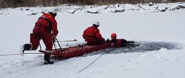 Strażacy przy pomocy sani lodowych ratują osobę, która wpadła do wody