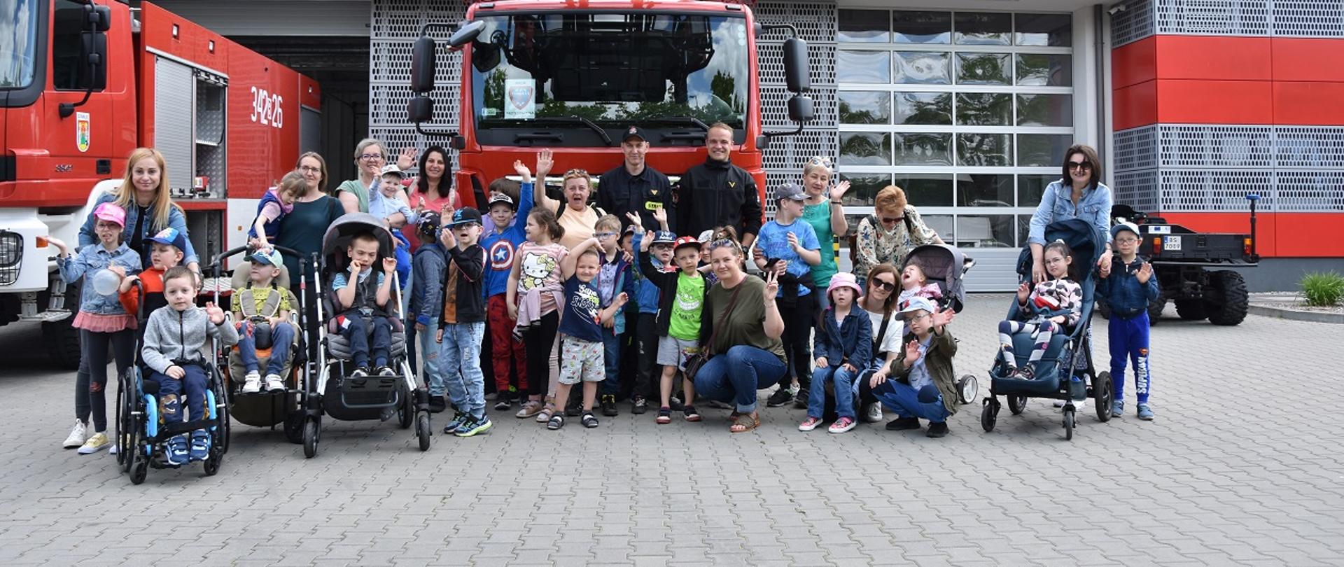Zdjęcie grupowe dzieci i strażaków na tle samochodu strażackiego