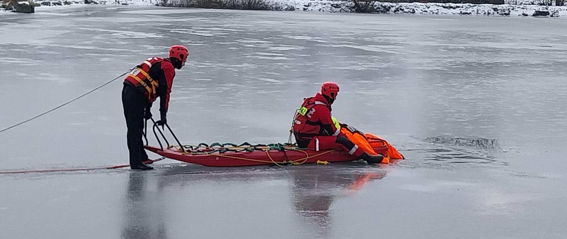 Zdjęcie przedstawia ratowników podczas ćwiczeń na lodzie z użyciem sań lodowych.