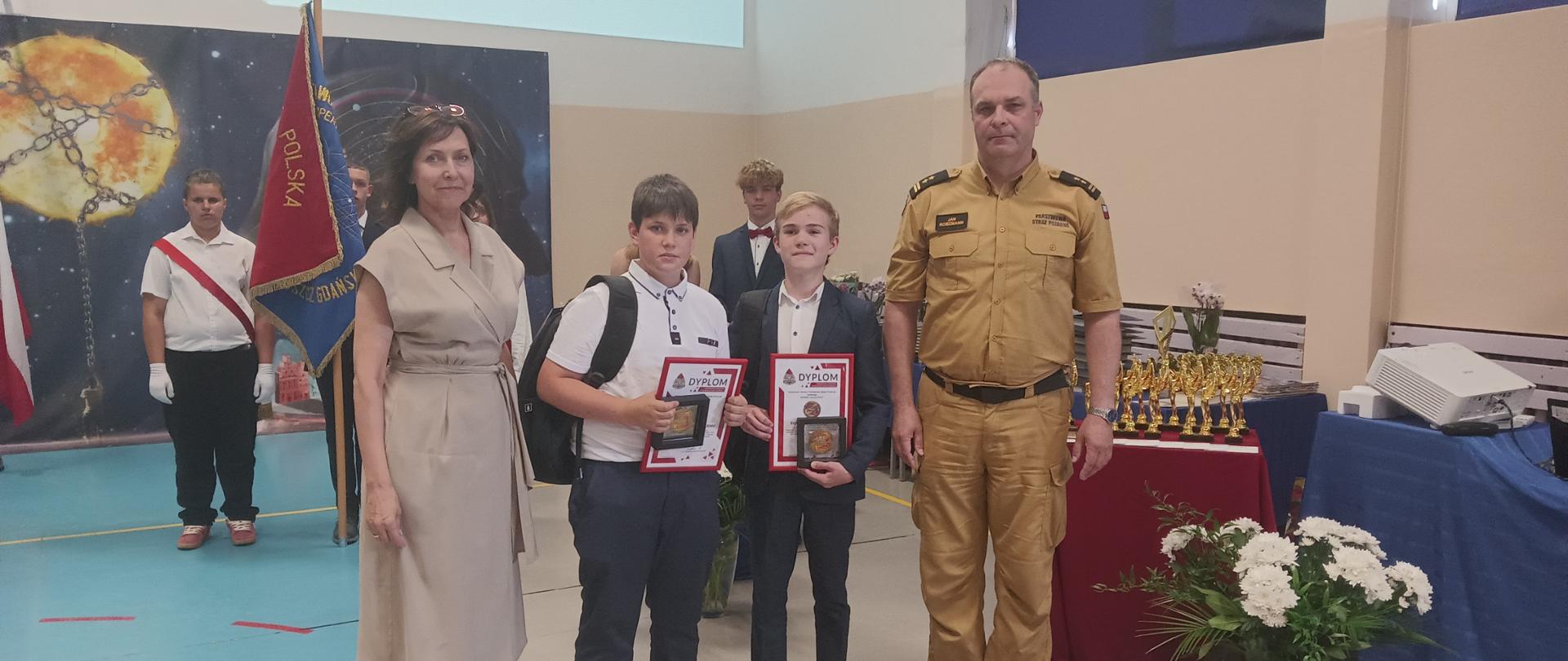 Na zdjęciu Komendant Powiatowy PSP oraz Dyrektor Szkoły Podstawowej nr 2 w Pruszczu Gdańskim z chłopcami wyróżnionymi odznaką Komendanta Głównego PSP „IUVENIS FORTI”.
