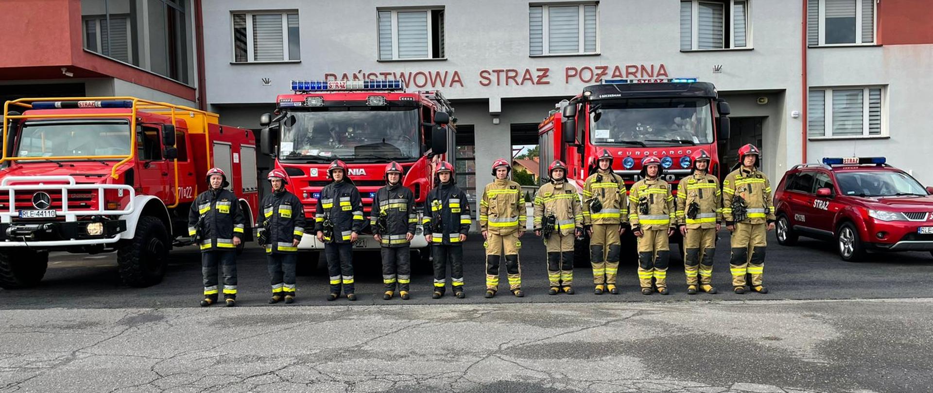 Na zdjęciu widzimy strażaków Komendy Powiatowej Państwowej Straży Pożarnej w Leżajsku w pełnym umundurowaniu bojowym na tle samochodów pożarniczych z włączona sygnalizacją dźwiękowa i świetlną