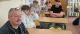 ludzie siedzą w ławkach w klasie