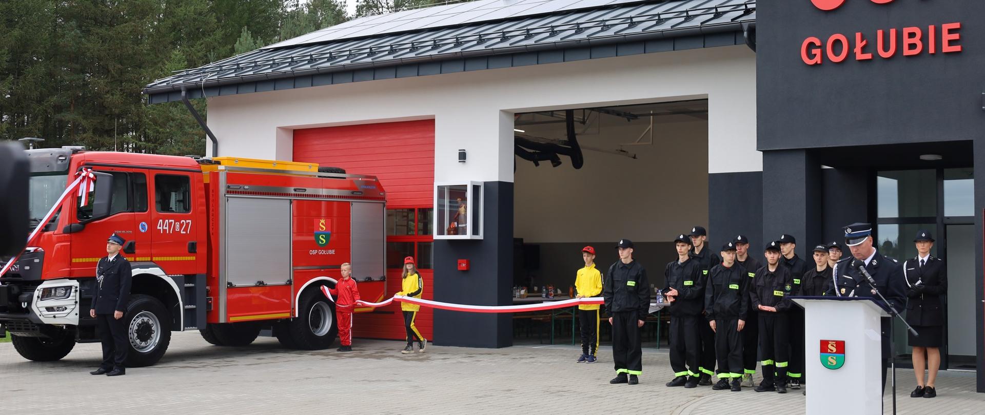 Wstęga przed garażem nowego budynku strażnicy trzymana przez członków MDP.
