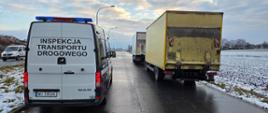 Samochód Inspekcji Transportu Drogowego stojący na mokrej drodze obok zatrzymanej żółtej ciężarówki, zimowe otoczenie.