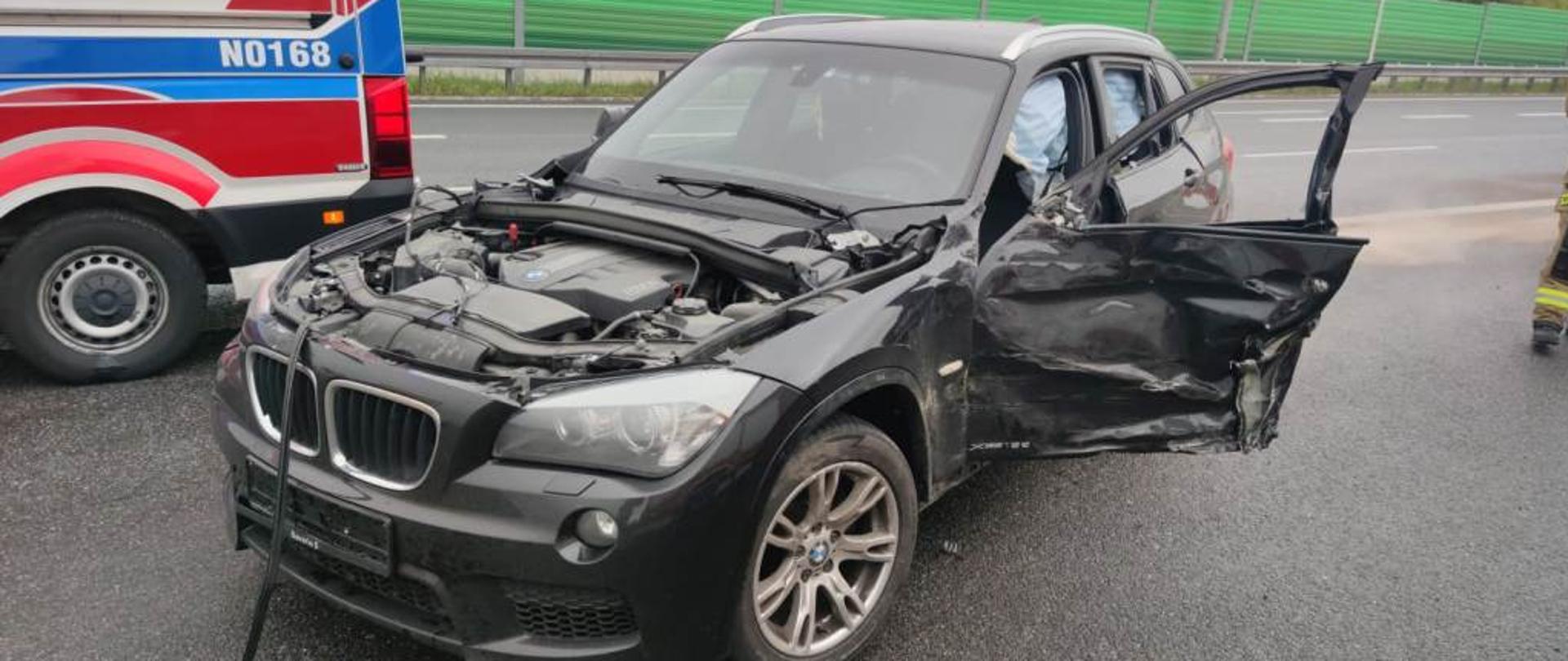 Widok samochodu osobowego marki BMW po kolizji z samochodem ciężarowym. 