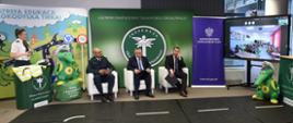 Lekcja bezpieczeństwa ruchu drogowego online dla uczniów z Ukrainy. Od lewej siedzą: Główny Inspektor Transportu Drogowego Alvin Gajadhur, Minister Infrastruktury Andrzej Adamczyk i Minister Edukacji i Nauki Przemysław Czarnek. Po prawej stronie monitor i wyświetlony na nim obraz z sali lekcyjnej.