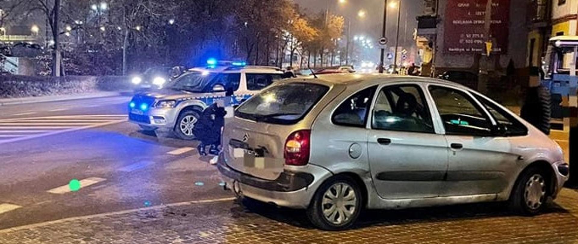 Pojazd osobowy i policyjny stoją na jezdni