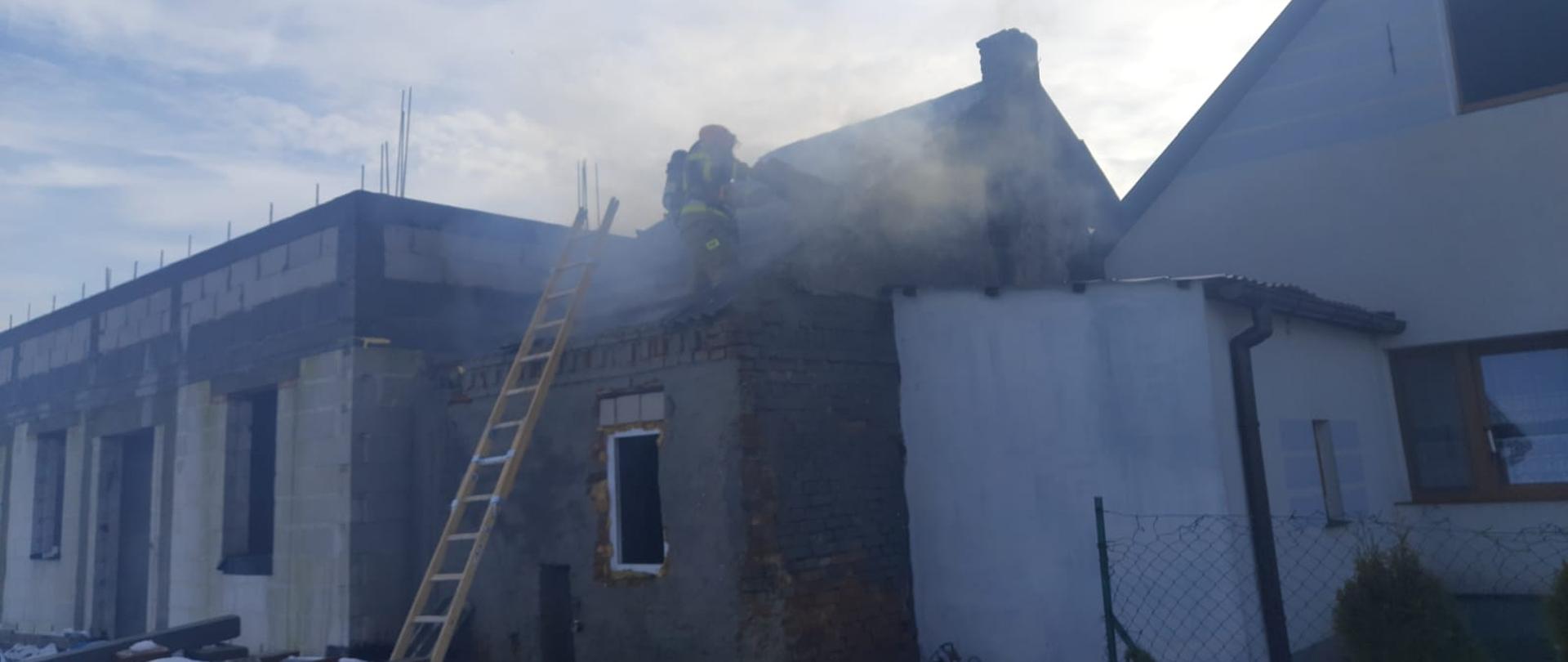 Na zdjęciu widać strażaka podczas prowadzenia działań na dachu 
