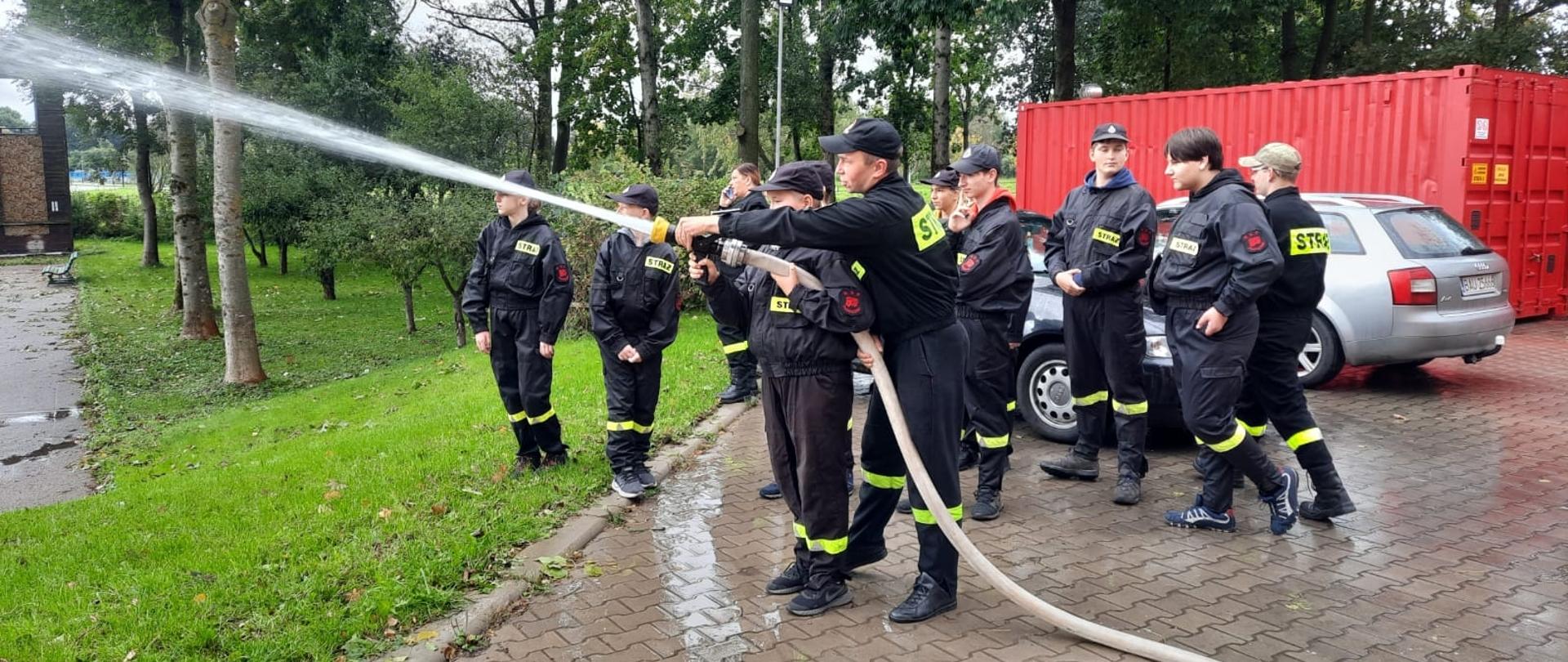 Polewanie wody przez dzieci z OSP Płociczno z węża W-52 i prądownicy typu Turbo