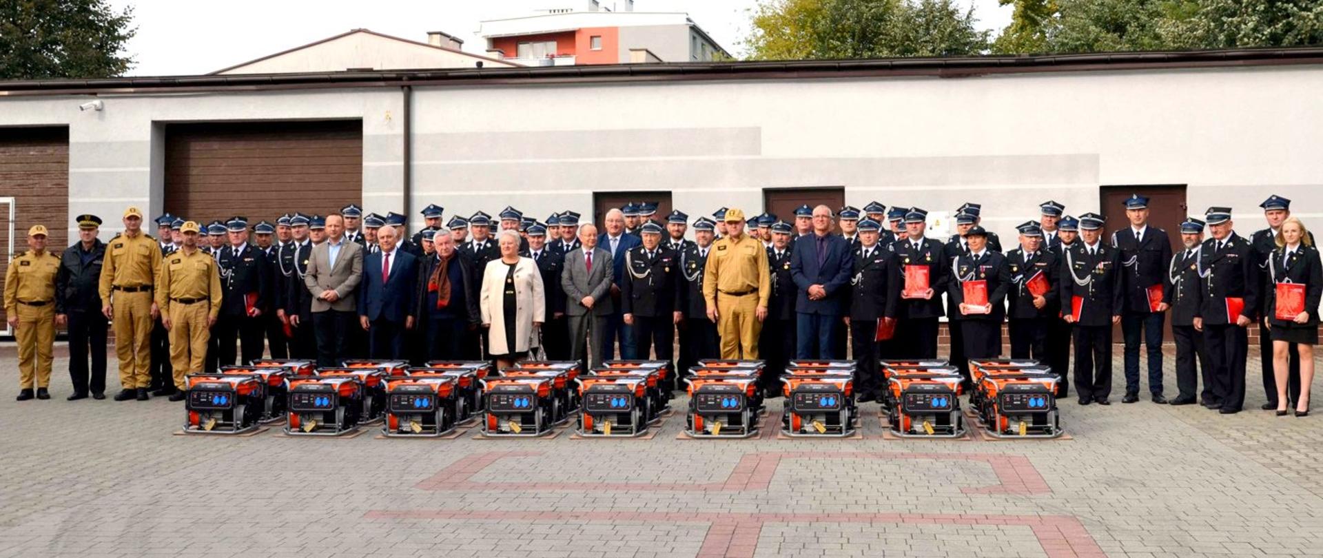 Zdjęcie zrobione na zewnątrz, na placu komendy straży pożarnej. Przekazanie agregatów prądotwórczych dla jednostek OSP.