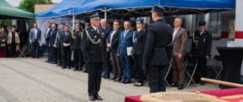 Dowódca uroczystości składa meldunek podczas jubileuszowego apelu przed strażnicą OSP Pawłowo Kościelne.