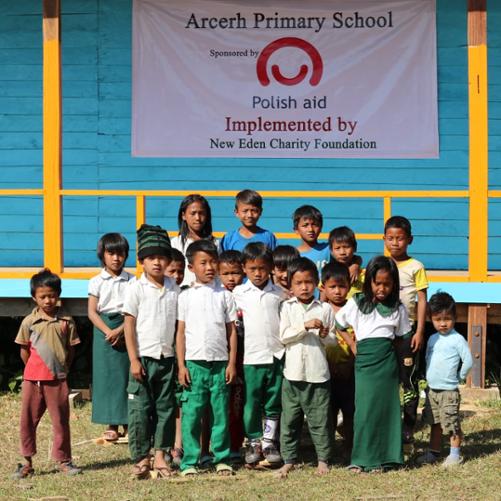 grupa dzieci przed budynkiem szkoły 