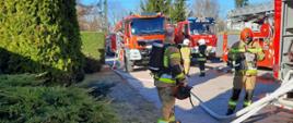 Zdjęcie przedstawia samochody pożarnicze i strażaków podczas akcji gaśniczej lakierni samochodów