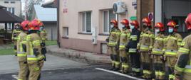 Zdjęcie przedstawia strażaków Jednostki Ratowniczo-Gaśniczej PSP w Lesku podczas uroczystej zbiórki z okazji Dnia Flagi Rzeczypospolitej Polskiej.