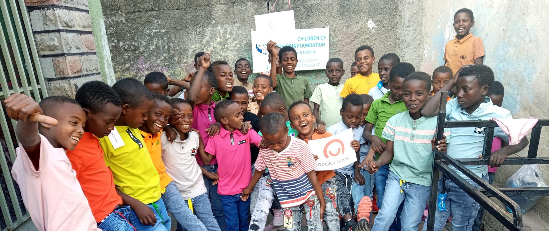 Czarnoskórzy chłopcy pozujący z logiem polskiej pomocy.