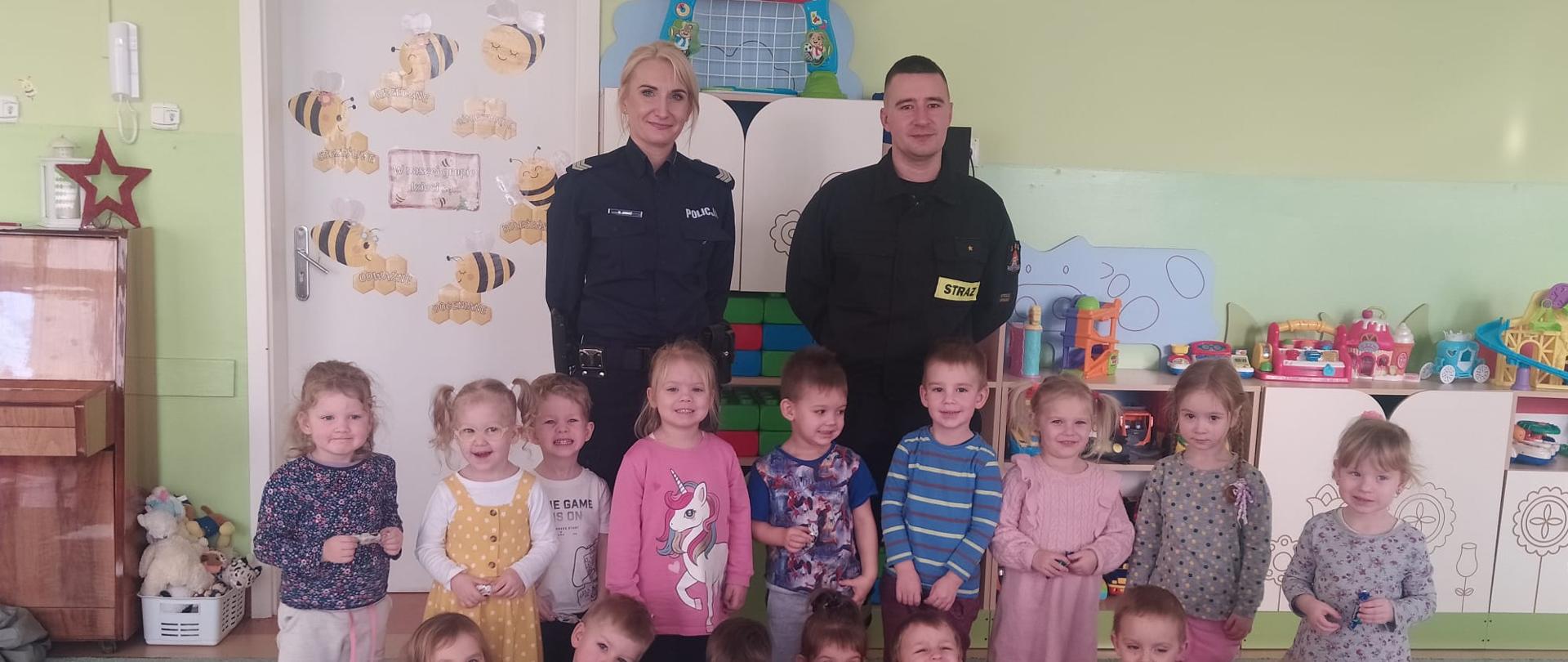 Na zdjęciu znajduje się strażak, policjantka oraz dzieci