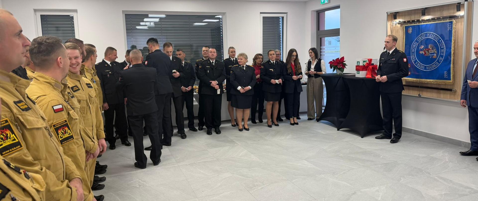 Spotkanie Wigilijne na sali tradycji, funkcjonariusze w mundurach wyjściowych przełamują się opłatkiem.