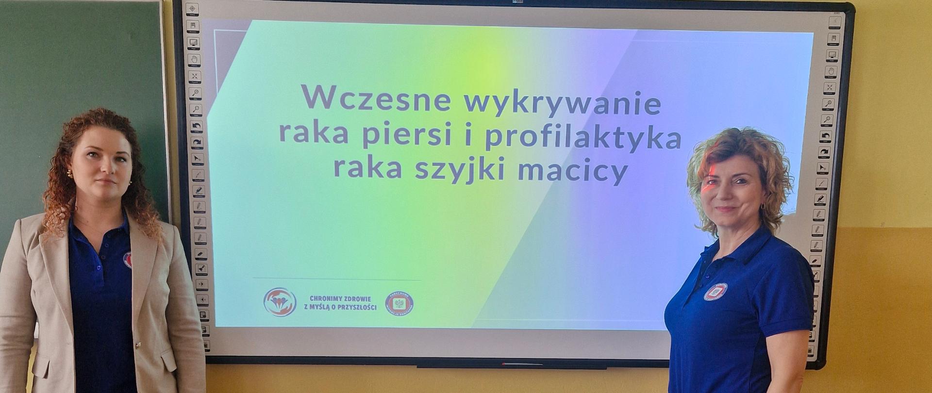 Dwie przedstawicielki Państwowego Powiatowego Inspektora Sanitarnego w Garwolinie na tle slajdu z napisem "Wczesne wykrywanie raka piersi i profilaktyka raka szyjki macicy".