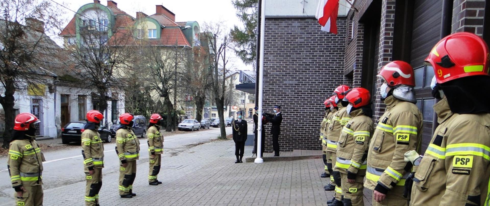 Obchody Narodowego Święta Niepodległości. Strażacy stojący na zbiórce na tle masztu flagowego.