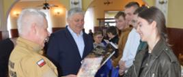 OTWP w Sobiałkowie. Świetlica wiejska w Sobiałkowie. Zastępca komendanta powiatowego PSP w Rawiczu wraz z burmistrzem wręczają dyplomy i upominki uczestnikom eliminacji. 