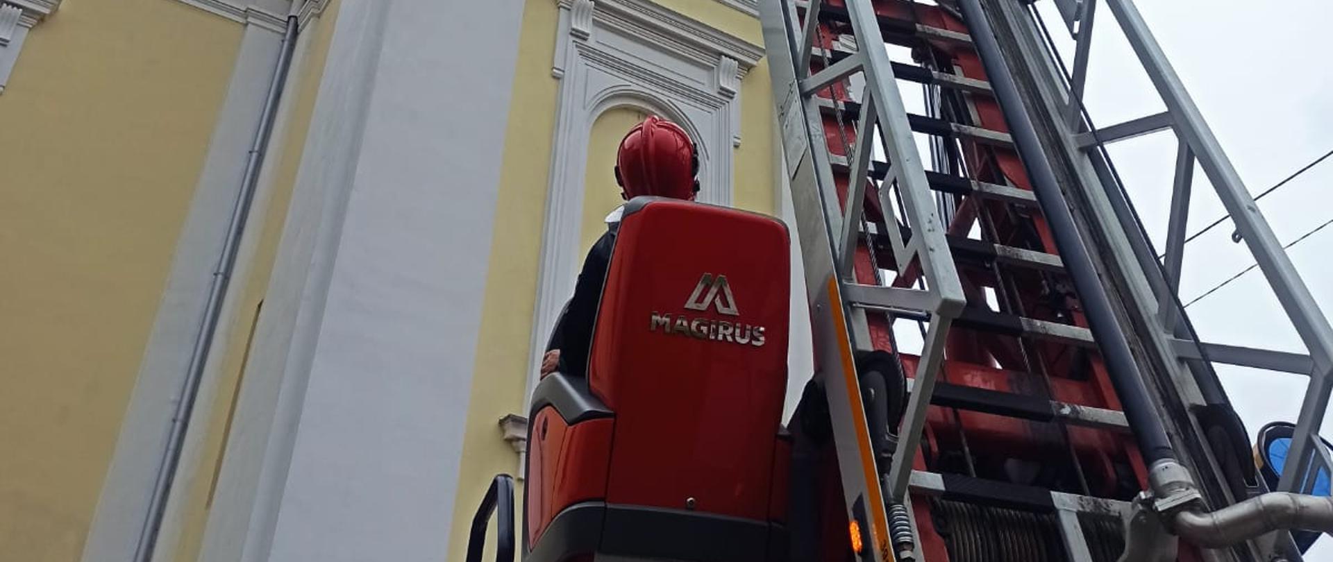 Strażak operujący drabiną mechaniczną przy budynku kościoła 