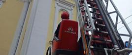 Strażak operujący drabiną mechaniczną przy budynku kościoła 