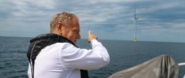 Premier Donald Tusk podczas wizyty na farmie wiatrowej Baltic Power. W tle turbina wiatrowa.