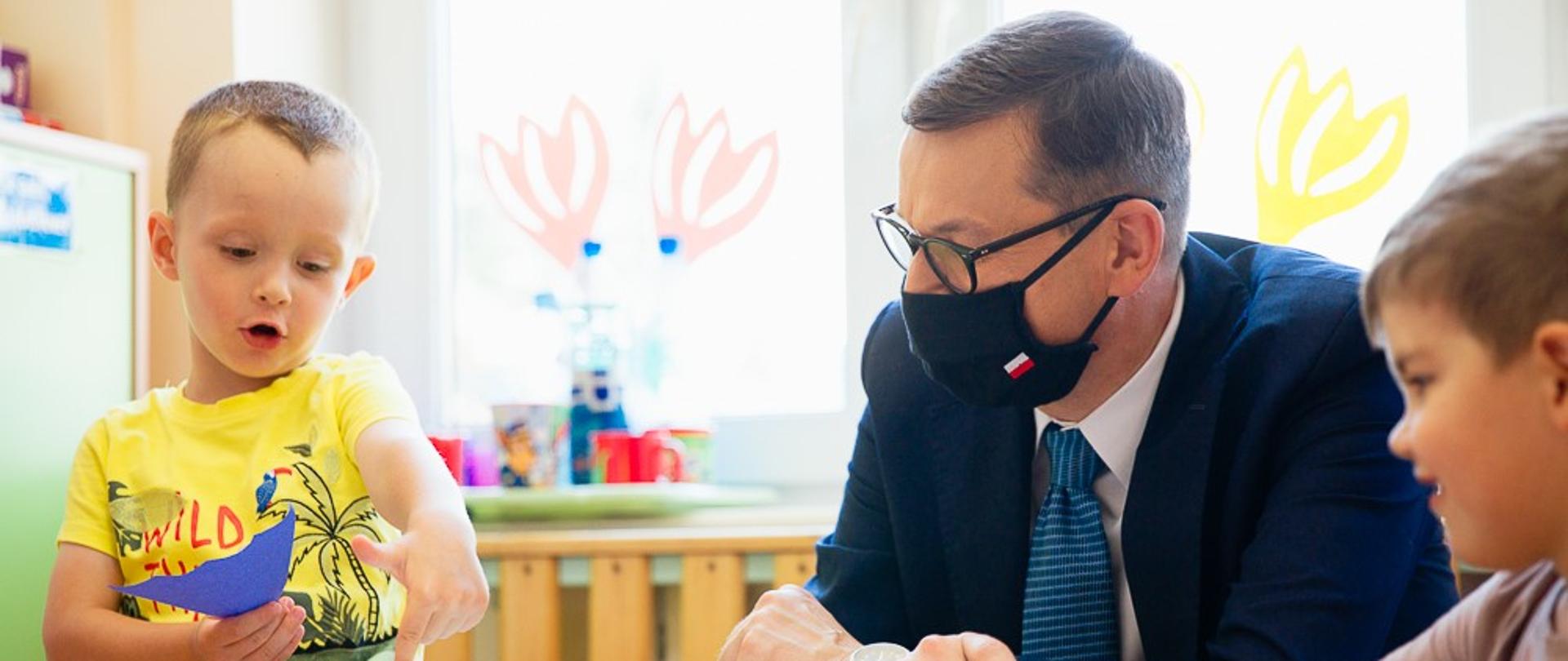 Premier siedzi wśród dzieci.