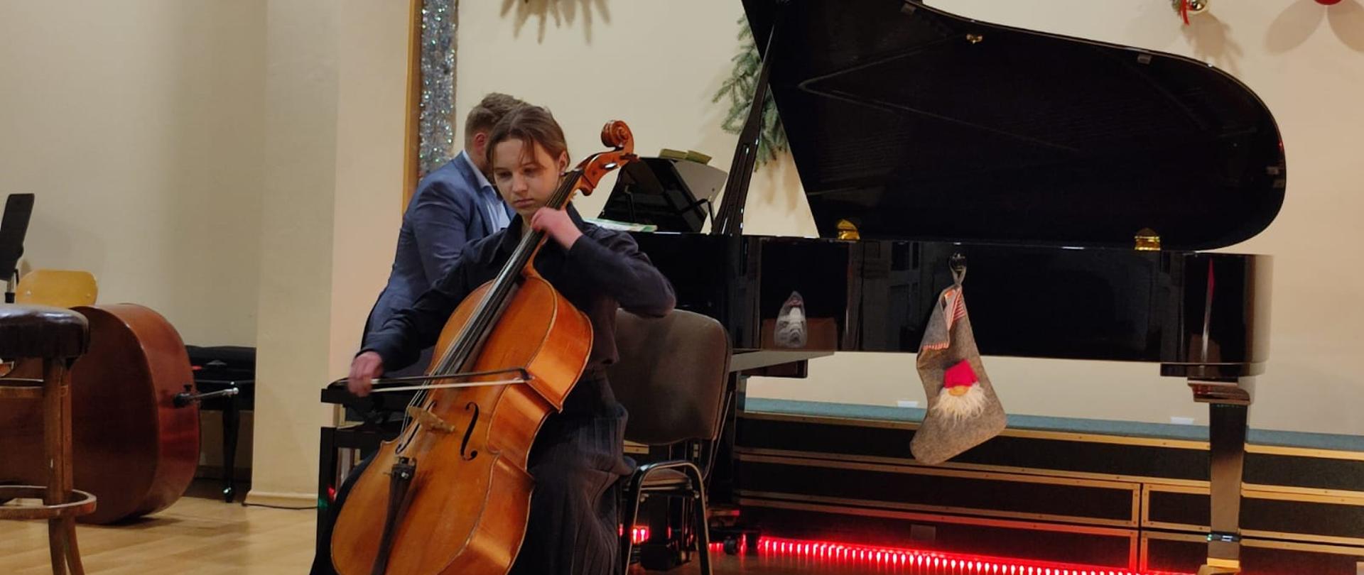 zdjęcie - uczennica na scenie grający na wiolonczeli, za nim fortepian